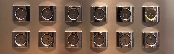 Bedieningselement in een lift, waarvan de getallen slecht leesbaar zijn.
